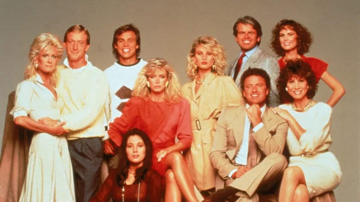 Cast of the TV show "Knots Landing" posing together in stylish 80s attire.